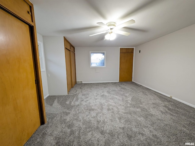 unfurnished bedroom featuring ceiling fan, carpet floors, and two closets