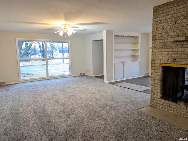 unfurnished living room featuring a brick fireplace, built in features, ceiling fan, and carpet