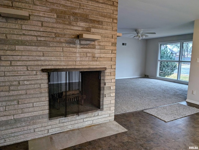 unfurnished living room with ceiling fan, dark carpet, and a brick fireplace