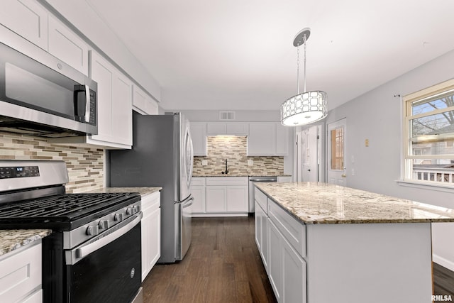 kitchen with dark wood-type flooring, decorative light fixtures, a center island, stainless steel appliances, and white cabinets