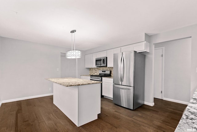 kitchen featuring light stone countertops, white cabinetry, appliances with stainless steel finishes, and decorative light fixtures