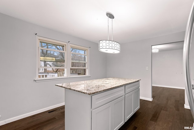 kitchen featuring white cabinetry, hanging light fixtures, dark hardwood / wood-style floors, light stone counters, and a kitchen island