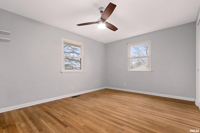 empty room featuring a wealth of natural light, ceiling fan, and light hardwood / wood-style flooring