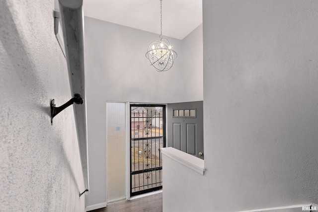 foyer featuring hardwood / wood-style flooring, a chandelier, and a towering ceiling