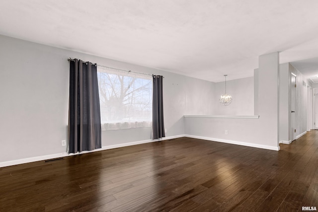 empty room with dark hardwood / wood-style flooring and a chandelier