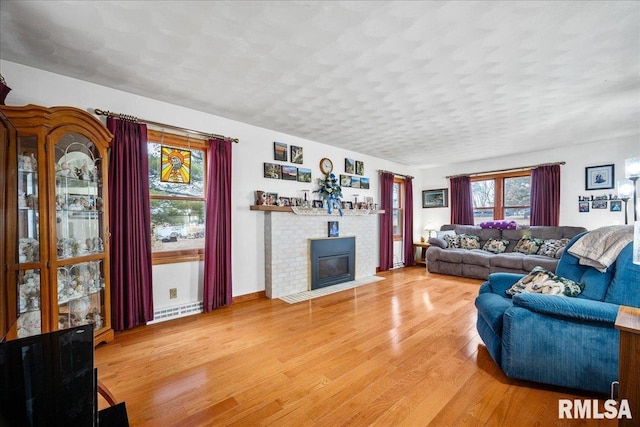 living room with a tiled fireplace, hardwood / wood-style floors, and a textured ceiling