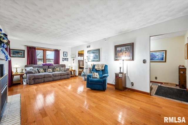 living room with a brick fireplace, hardwood / wood-style floors, and a textured ceiling