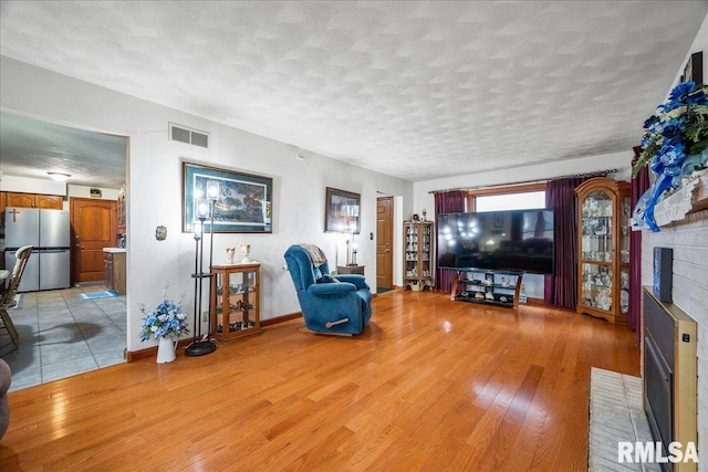 living room featuring a fireplace, a textured ceiling, and light wood-type flooring