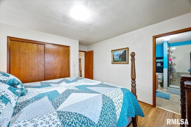 bedroom with ensuite bath, light hardwood / wood-style floors, a closet, and a textured ceiling