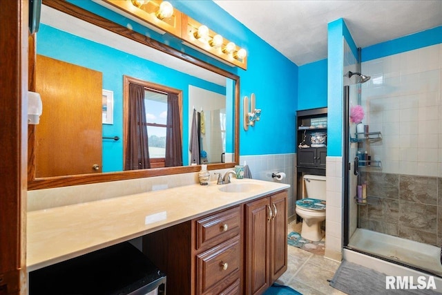 bathroom featuring tile patterned flooring, tile walls, vanity, a shower with shower door, and toilet