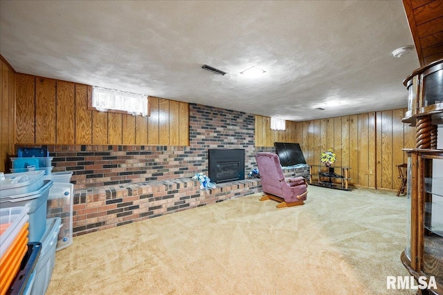 sitting room with light carpet, a brick fireplace, wooden walls, and a textured ceiling