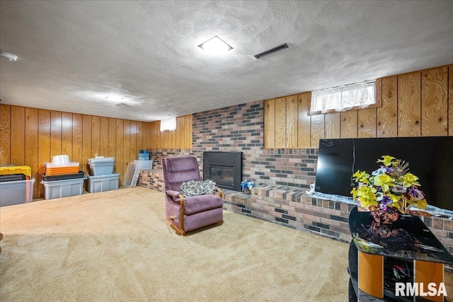 living room featuring carpet floors, a textured ceiling, a fireplace, and wood walls