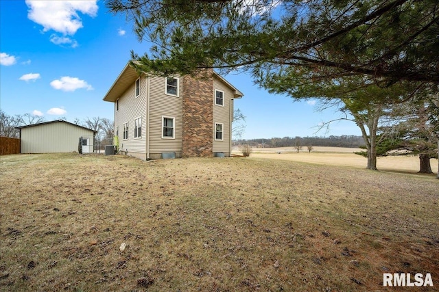 rear view of house featuring central AC and a lawn