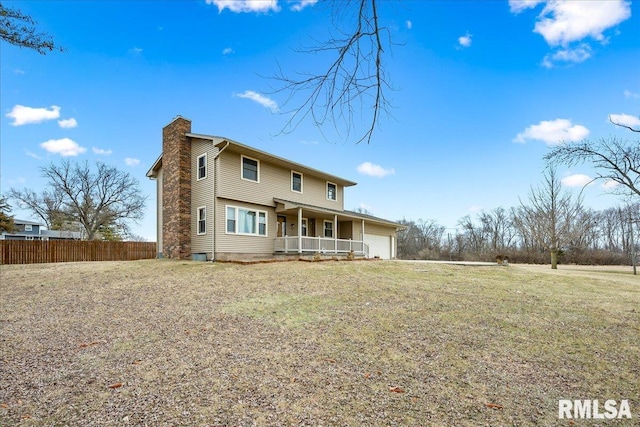 back of property featuring a garage, a yard, and covered porch