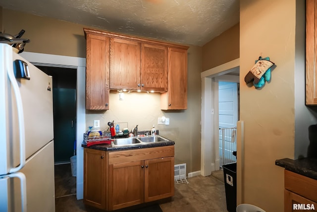 kitchen with sink, white fridge, and a textured ceiling