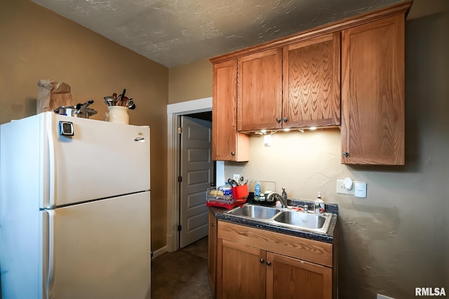 kitchen with sink, a textured ceiling, and white refrigerator