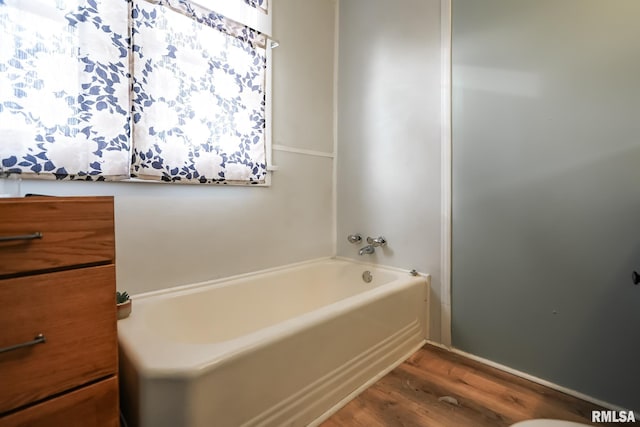 bathroom with hardwood / wood-style flooring and a tub