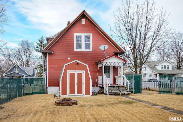 view of front of house with a storage shed, a front lawn, and an outdoor fire pit