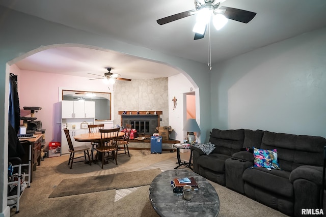 living room with ceiling fan, light colored carpet, and a fireplace