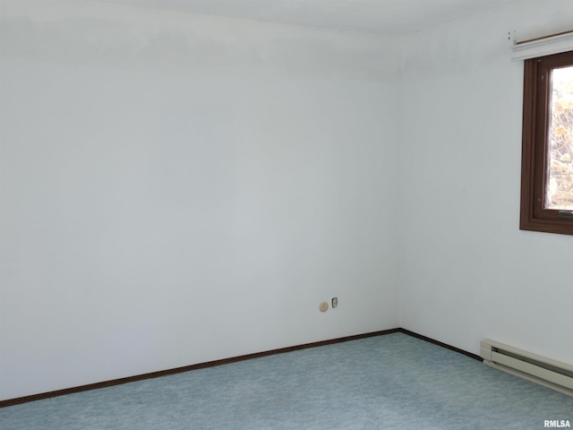 carpeted spare room with a baseboard heating unit