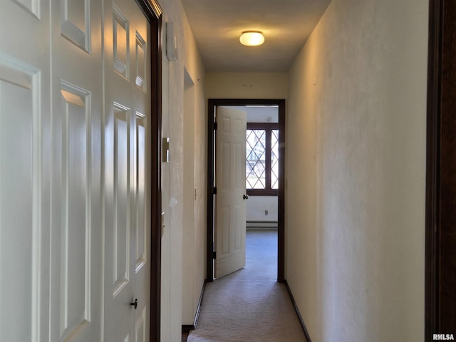 hallway with baseboard heating and light colored carpet