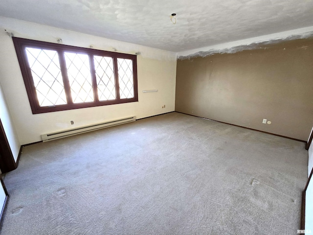 carpeted empty room featuring a baseboard heating unit and a textured ceiling