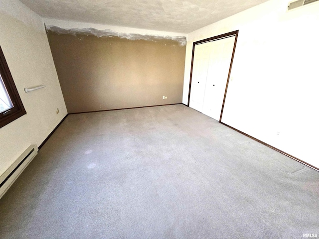 unfurnished bedroom featuring a closet, a textured ceiling, and a baseboard heating unit