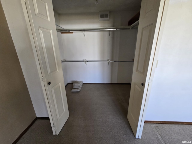 spacious closet with dark colored carpet