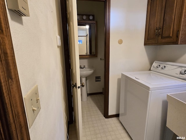 clothes washing area featuring sink, washer / dryer, and cabinets