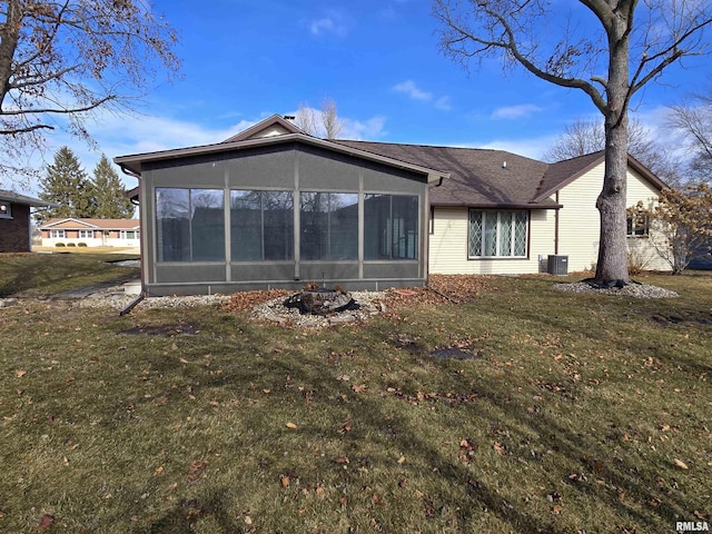 rear view of property featuring a sunroom, a yard, and central air condition unit