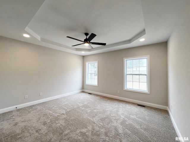 empty room with baseboards, visible vents, carpet flooring, and a raised ceiling