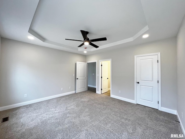 unfurnished bedroom with baseboards, visible vents, carpet, and a raised ceiling