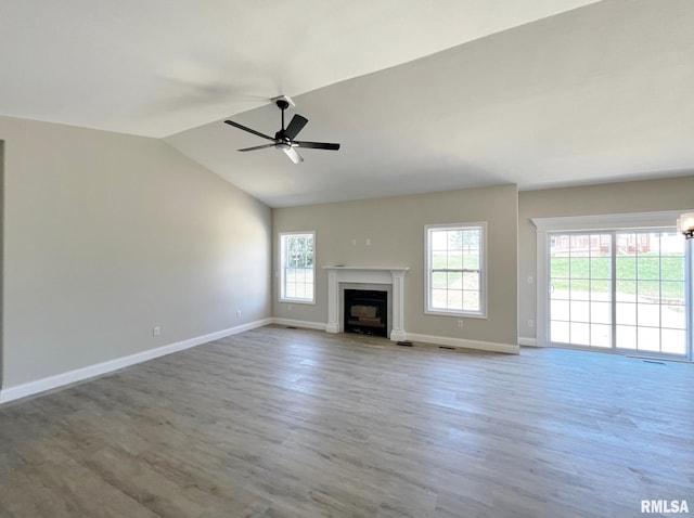 unfurnished living room with a fireplace with flush hearth, baseboards, ceiling fan, wood finished floors, and vaulted ceiling