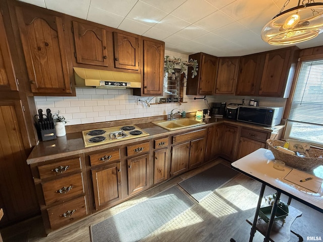 kitchen featuring extractor fan, pendant lighting, sink, backsplash, and cooktop