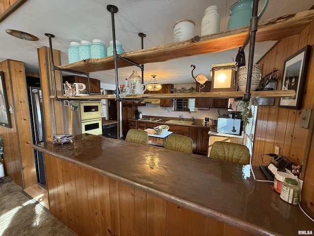 kitchen featuring sink, black electric stovetop, and wooden walls