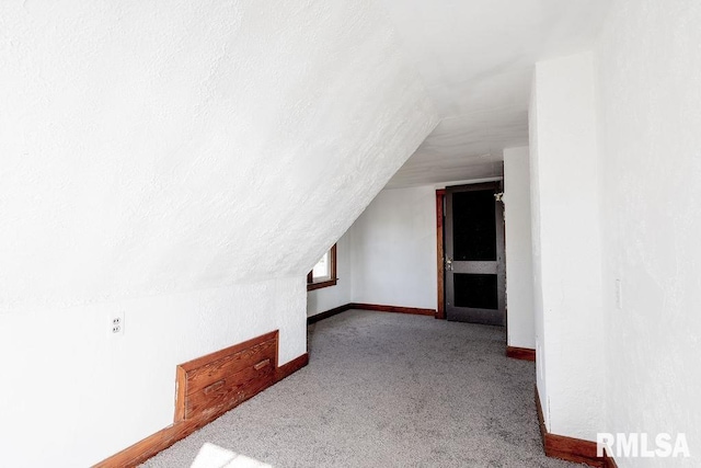 additional living space featuring lofted ceiling and light carpet