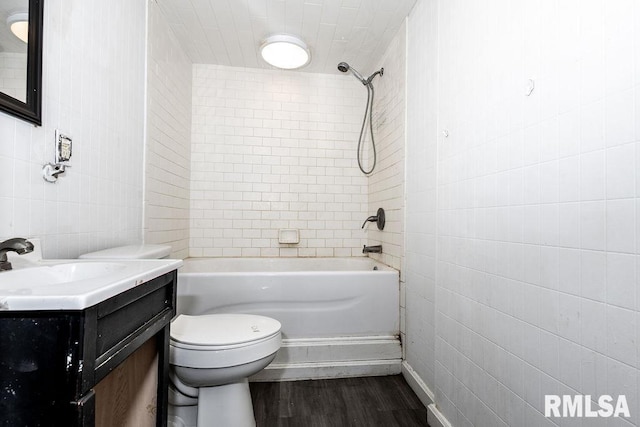 full bathroom featuring toilet, tiled shower / bath, wood-type flooring, tile walls, and vanity