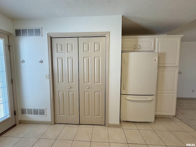 kitchen with light tile patterned floors, white cabinets, and white fridge