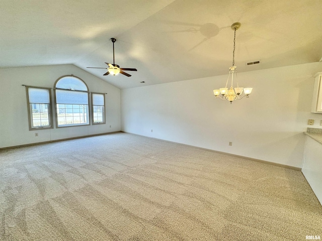 carpeted spare room featuring lofted ceiling and ceiling fan with notable chandelier