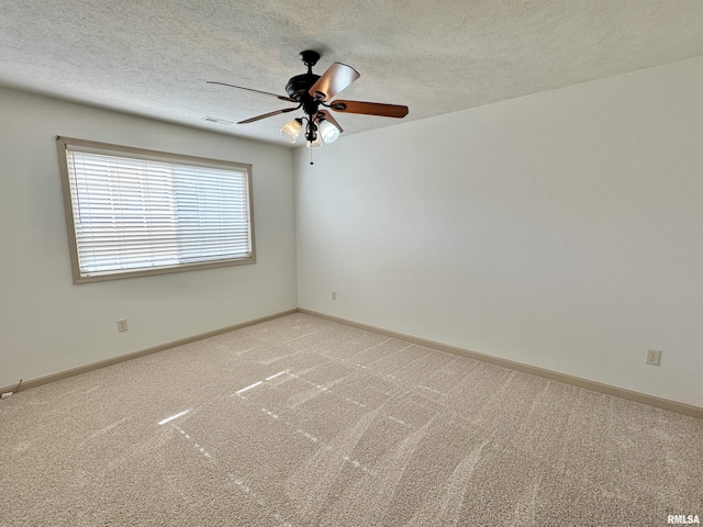 empty room featuring ceiling fan, light colored carpet, and a textured ceiling