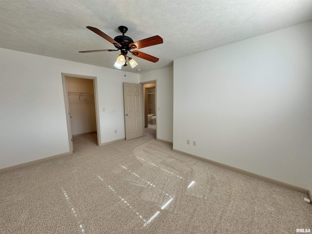 unfurnished bedroom with carpet floors, a spacious closet, ceiling fan, a textured ceiling, and a closet