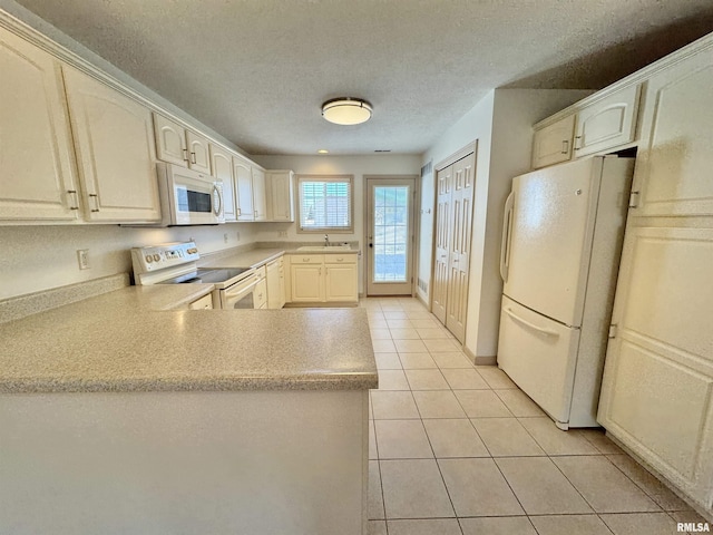 kitchen with sink, light tile patterned floors, white appliances, kitchen peninsula, and a textured ceiling