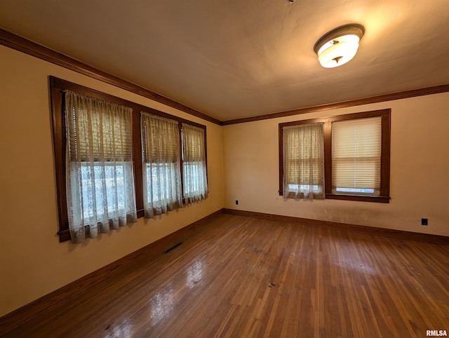 unfurnished room featuring ornamental molding, wood finished floors, and visible vents