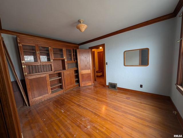 unfurnished living room featuring ornamental molding, visible vents, baseboards, and wood finished floors