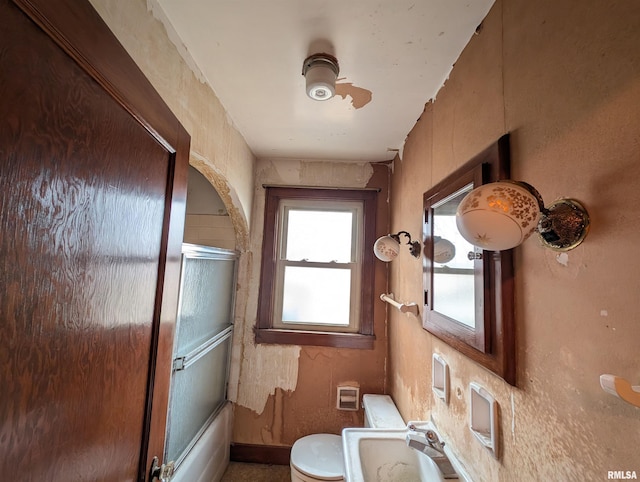 bathroom with toilet, shower / bath combination with glass door, and a sink