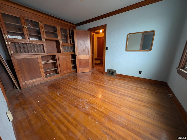 unfurnished living room featuring ornamental molding, visible vents, baseboards, and wood finished floors