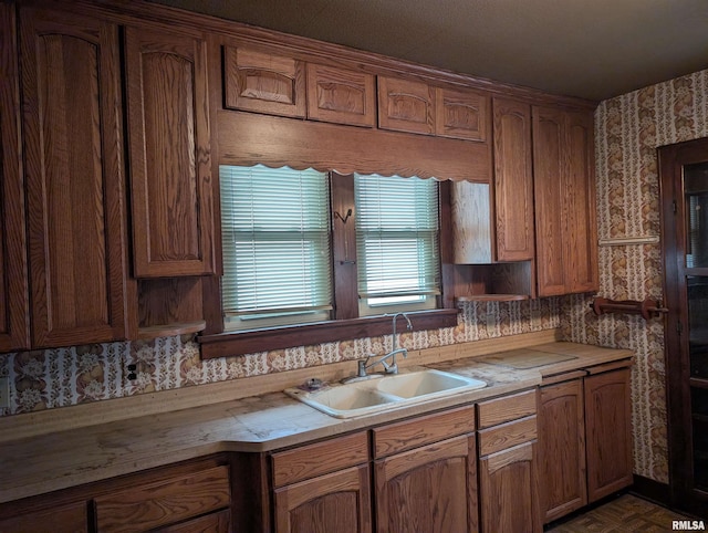 kitchen with wallpapered walls, light countertops, and a sink