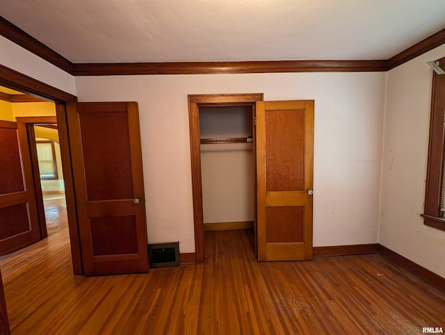 unfurnished bedroom featuring ornamental molding, hardwood / wood-style floors, and a closet