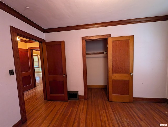 unfurnished bedroom with ornamental molding, dark hardwood / wood-style floors, and a closet