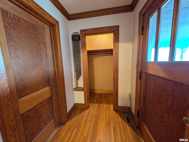 hallway with visible vents, crown molding, light wood-style flooring, and baseboards